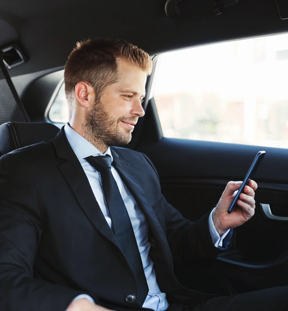 Professional chauffeur standing next to a luxury limousine